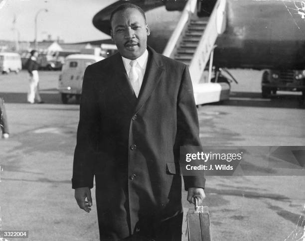 American civil rights campaigner Martin Luther King arriving at London Airport. He is in England to be the chief speaker at a public meeting about...