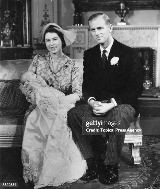 Princess Elizabeth holding her daughter Princess Anne at her christening in Buckingham Palace, with the Duke of Edinburgh at her side.