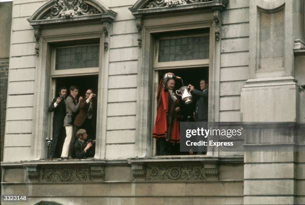 Photographers jostle for space in a window at Chelsea Town Hall, London, as Chelsea's mayor pours champagne into the FA Cup trophy held up by...
