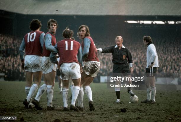 West Ham United players Geoff Hurst and Billy Bonds turn to look behind them as they make a wall for a free kick during the fourth round FA Cup...