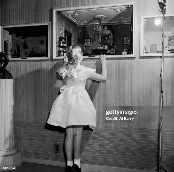 Collection of miniature rooms belonging to the Helena Rubinstein collection being examined by a girl on tip-toes.