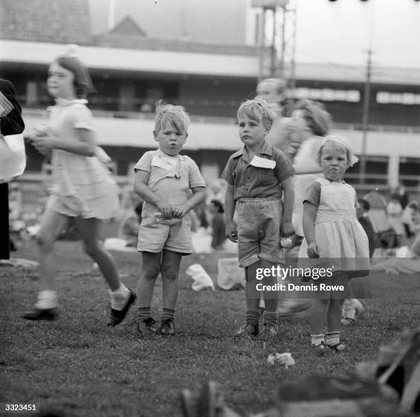 Three children stand frozen in time as others run past in a blur. They are attending a party for sick and needy children, at Sydney Cricket Ground,...