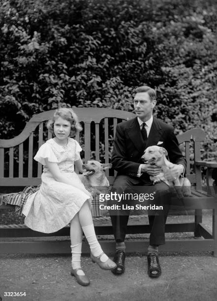 George, Duke of York and Princess Elizabeth sitting on a bench with their corgi dogs in the grounds of their London home, 145 Piccadilly.
