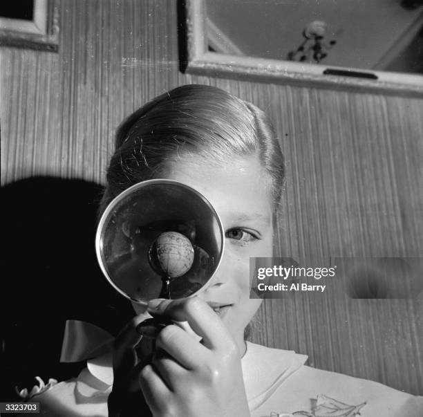 Miniature globe belonging to the Helena Rubinstein collection being examined with the help of a magnifying glass.