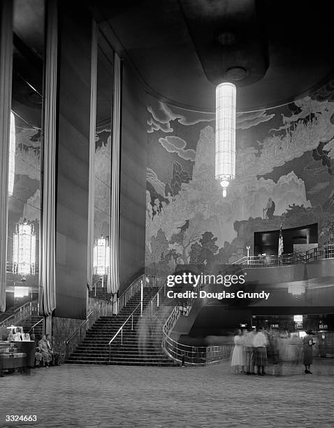 The grand staircase, with a huge vertical Art Deco chandelier and wall mural in the lobby of Radio City Music Hall in New York City.