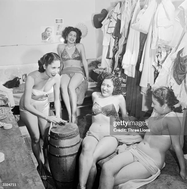 Bikini-clad chorus girls in a burlesque show relax backstage by beating out a rythm on a native drum, at the Tivoli Theatre, Mexico City.