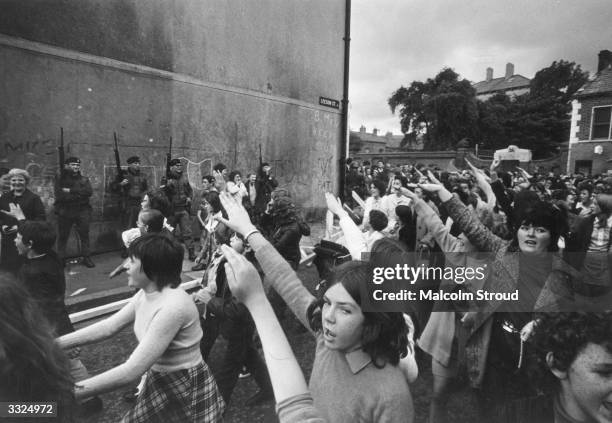 Crowd of demonstrators passing British soldiers in Leeson St in the Falls Road area of Belfast.