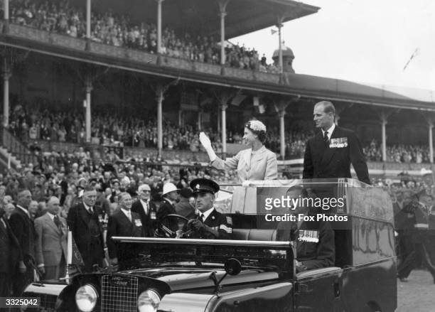 Queen Elizabeth II and Prince Philip wave to crowds as they are driven on a circuit of Melbourne cricket ground as part of their Australian tour. The...