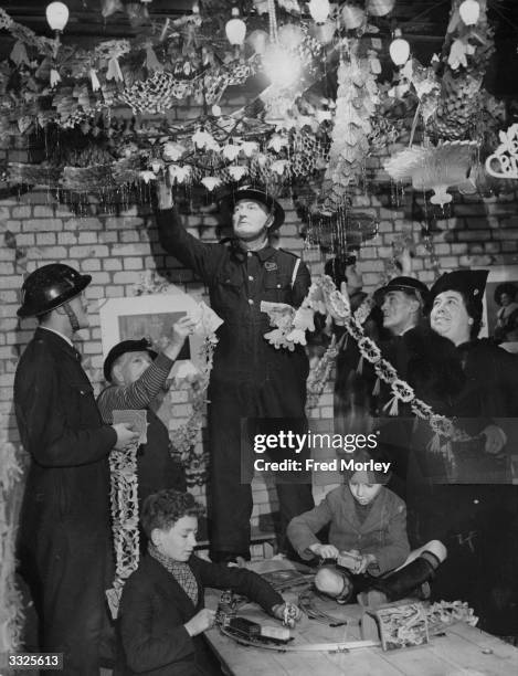 Members hang Christmas decorations in a cubicle of a shelter beneath a cinema in South London.