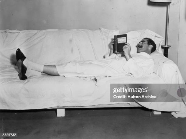 American comic Groucho Marx reading 'Principals of Education' during a break in the filming of 'Duck Soup'.