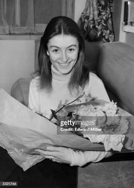 French actress Anouk Aimee with a bouquet of flowers after arriving at the Athenaeum Court, Piccadilly, London, where she is to take part in the...
