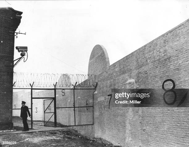 Prison officer walks below a closed circuit TV camera at the newly built security block at Parkhurst Prison, built to house high-risk prisoners.