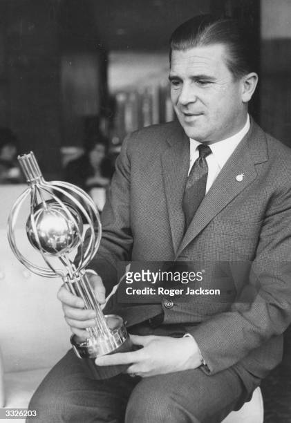 Real Madrid and Hungarian soccer star Ferenc Puskas admires the silver trophy specially made as a prize for the winners of the charity game between...