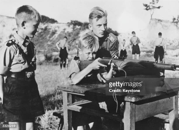 Eleven year old boys in the Hitler Youth organization learning how to fire a rifle.