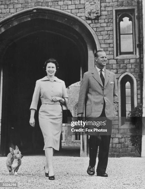 Queen Elizabeth II and Prince Philip, the Duke of Edinburgh, with the Queen's corgi Sugar walking near the George IV gateway at Windsor Castle.