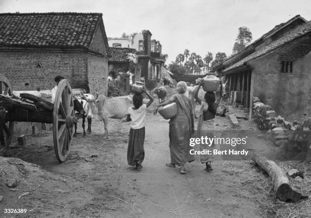 Three 'untouchables' carry water back to their huts in the village of Mudichur, 30 miles from Madras in south east India. Original Publication:...