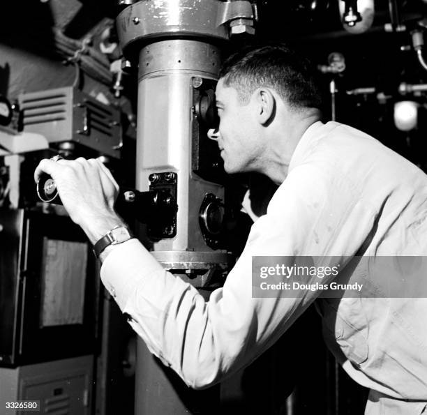 First officer in a submarine uses a periscope during torpedo firing practice.