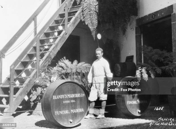 Casks containg madeira wine at a Blandy's a Funchal winery. The worker is wearing unusual headgear with a sharp spike on the crown.