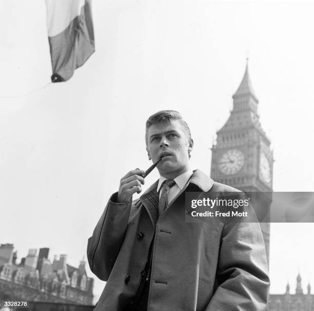 Comedian Mike Yarwood smoking his pipe in front of Big Ben's clocktower, London.