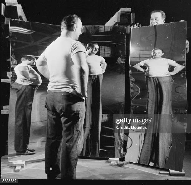 Chubby man sees himself a few stone lighter in a distorting mirror made at the Pittsburgh Plate Glass Co.