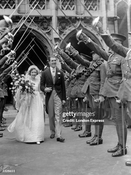 Lieutenant Oliver Pemberton Stedall and his wife Catherine Trevor Williams pass through a 'guard of honour' after their wedding at St Margaret's,...