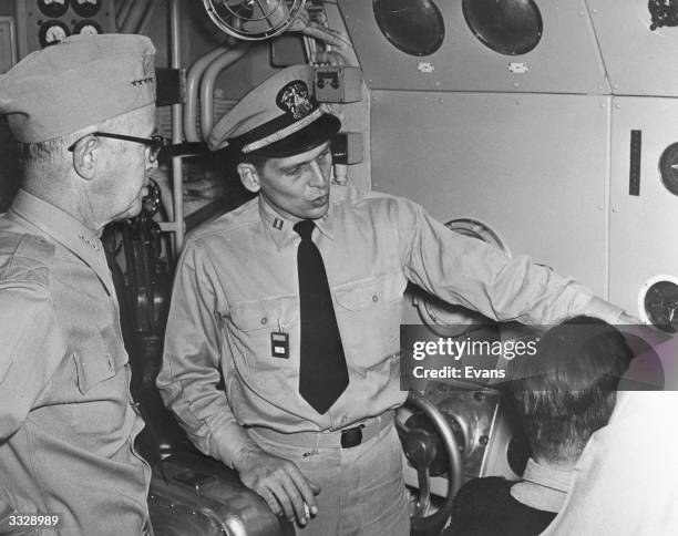 The executive officer of the World's first nuclear powered vessel, the submarine USS Nautilus, explains the depth gauges to Admiral Robert B Carney.