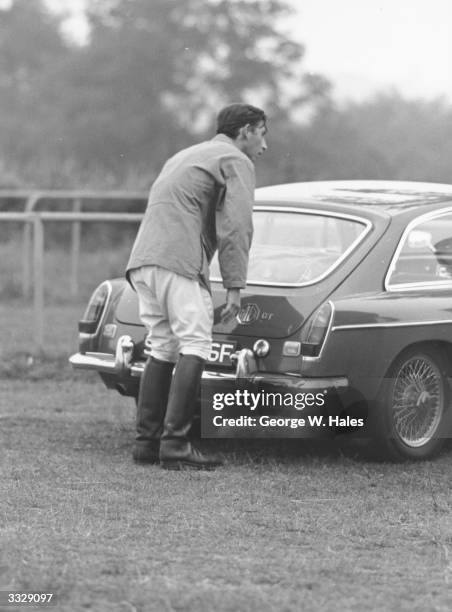 Charles, Prince of Wales closing the boot of an MG sports car at Cowdray Park, Midhurst, Sussex after competing in a polo match.