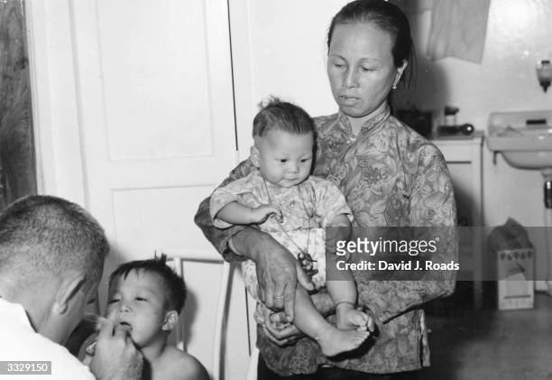 Chinese woman and two children at a clinic run by US doctor James Turpin aboard a junk in a typhoon shelter in Hong Kong. The influx of refugees from...