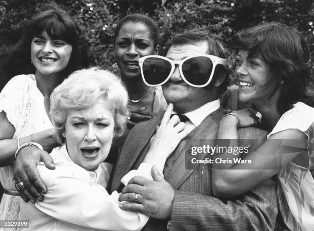 Comedian Les Dawson wearing an enormous pair of sunglasses much to comedy actress June Whitfield's amusement. Joining in the fun are Isla St Clair,...