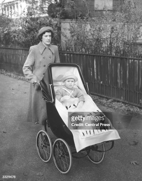 Prince Charles, heir to the British throne riding in his pram pushed by his nanny, Mabel Anderson.