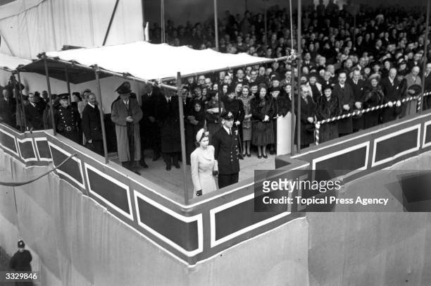 Princess Elizabeth, accompanied by Lieutenant Mountbatten, before launching a Cunard White Star liner, 'Caronia', at Clydebank, Scotland. She is the...