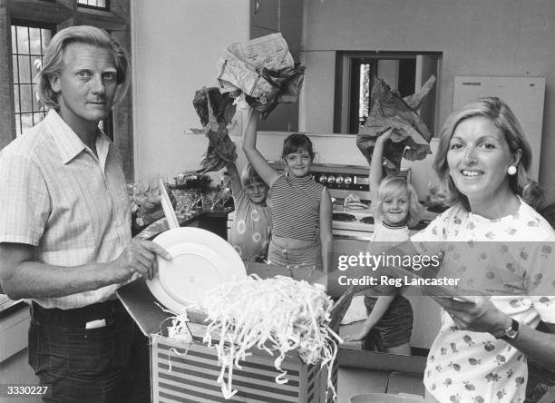 Politician Michael Heseltine with his wife and children unpacking boxes in the kitchen of their new home.