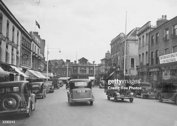 Traffic moves along a street lined with parked cars in Taunton, Somerset.