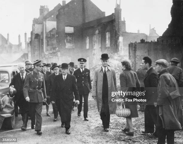 His Majesty King George VI and Herbert Morrison , the home secretary and minister of home security inspect air-raid damage in war-time Coventry. They...