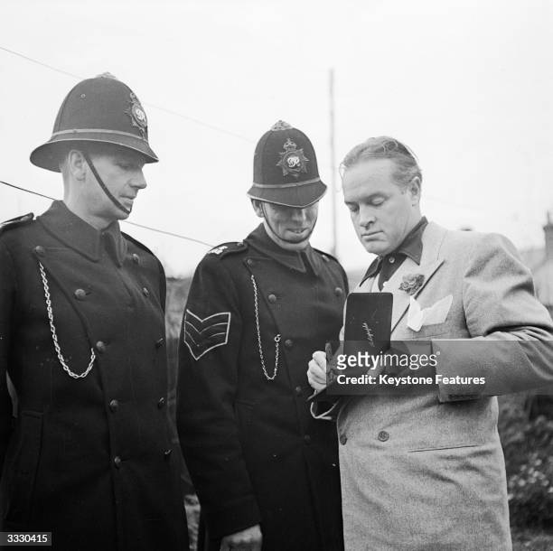 American comic actor Bob Hope signs autographs for the local police sergeant and constable during the star's trip to visit family in Hitchin,...