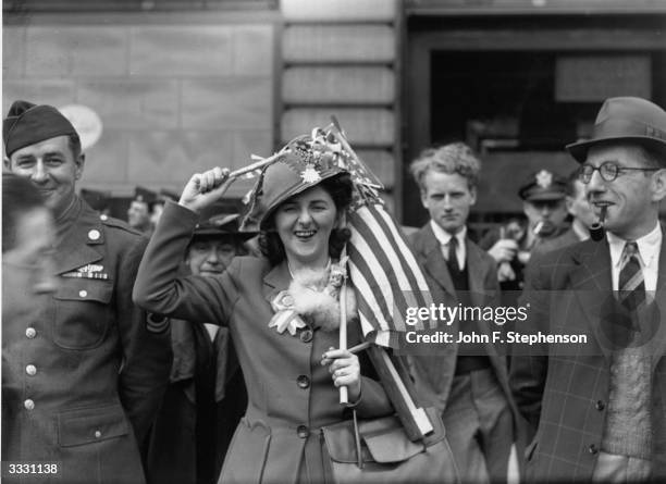 Woman holding an American flag over her head during VE day celebrations in Piccadilly Circus, London.