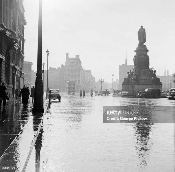 Connell Street in Dublin on a rainy day. On the right is a large statue of Daniel O'Connell, leader of the fight to win political rights for Irish...
