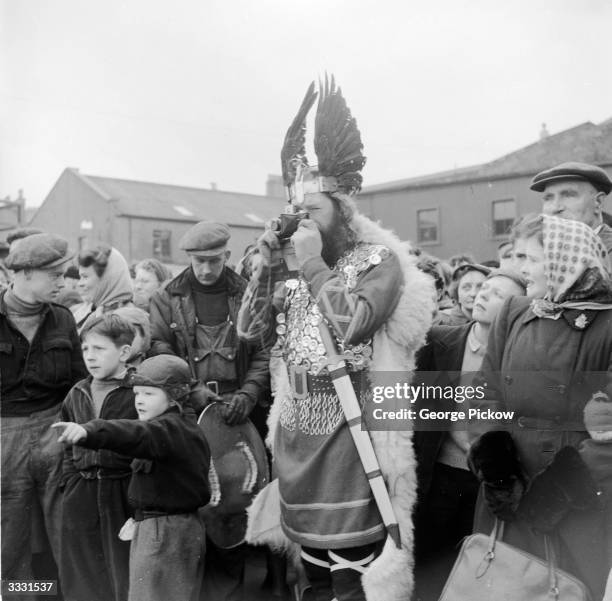 Member of the Lerwick 'Up-Helly-Aa' committee in Viking costume takes a photograph during celebrations commemorating the 9th-century Norse invasion...