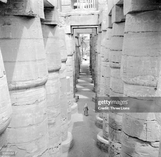 Man standing in the Column Hall of the Great Temple of Amon at Karnak, built by Amenophis III.