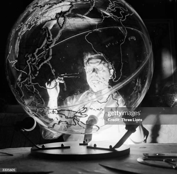 Geographer employed by the Farquhar company in Philadelphia at work on a three-foot diameter transparent globe. He is surveying the area off the...