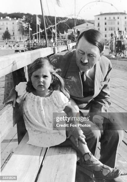 German dictator Adolf Hitler sitting on a bench with Helga Goebbels, daughter of Nazi propagandist Paul Joseph Goebbels.