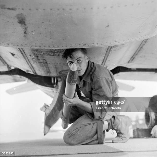 Rockets being loaded into the underside of an F-86D fighter jet at McGuire Air Force Base in New Jersey.