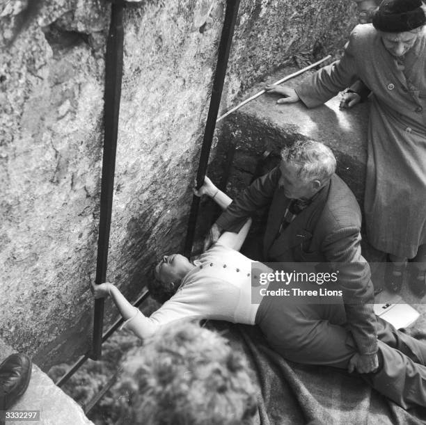 With the help of the curator of the stone, a woman bends to kiss the Blarney Stone at Blarney Castle in County Cork.