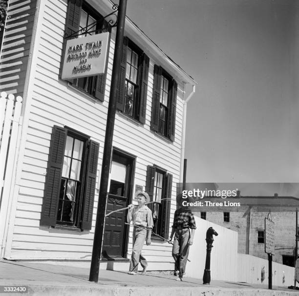 'Tom Sawyer' and 'Huck Finn' stroll past the childhood home of Mark Twain on a fishing expedition. The house in Hannibal, Missouri,where Twain spent...