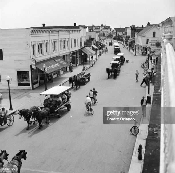 Horse drawn carts and bicyles passing along the main street of Mackinac Island, Michigan where the use of cars is prohibited.