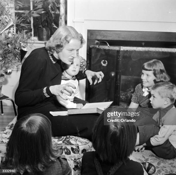 English novelist and magazine columnist Monica Dickens , reading to her children from 'A Christmas Carol' by her grandfather Charles Dickens.