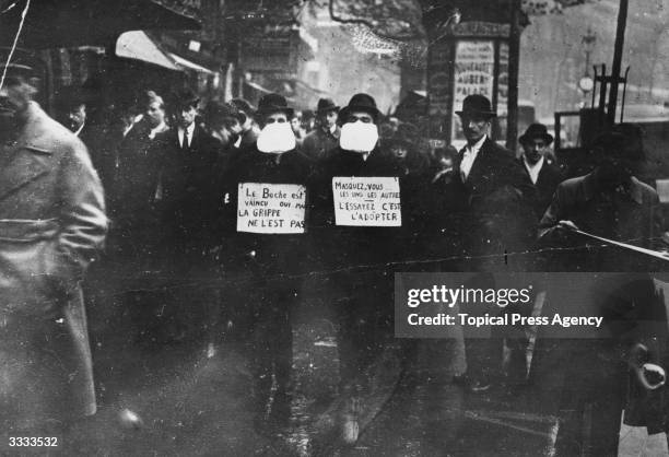 Two men wearing and advocating the use of flu masks in Paris during the Spanish flu epidemic which followed World War I.