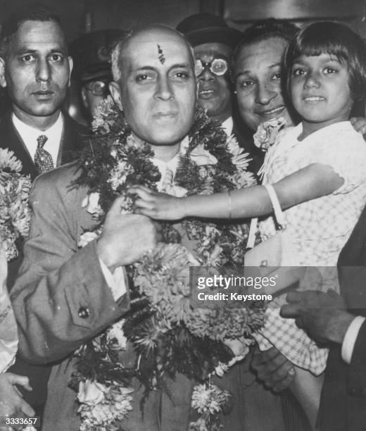 Garlanded Jawaharlal Nehru on parole from political imprisonment arrives at Victoria station, London to a hero's welcome.