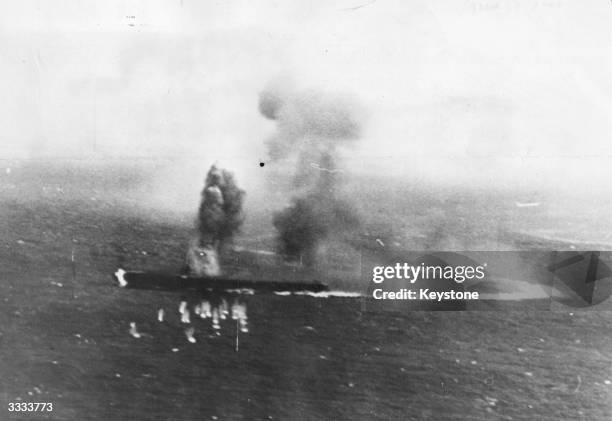 Burning Japanese aircraft carrier Shokaku takes evasive action to avoid American bombs during the Battle of the Coral Sea. The line of her wake shows...