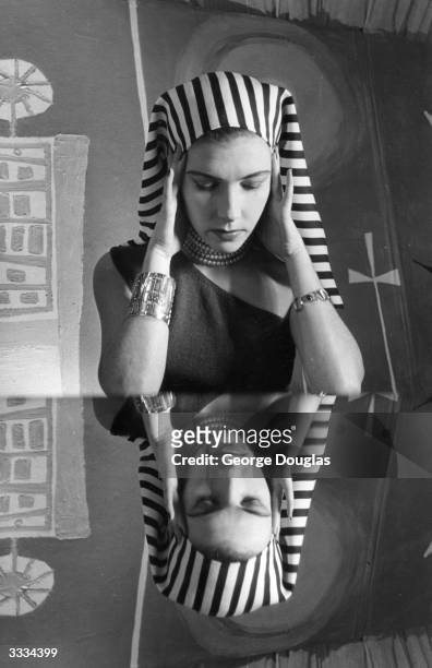 Woman modelling clothes at a student fashion show for charity, held at the Glasgow School of Art, July 1952. She is wearing an Egyptian-style striped...